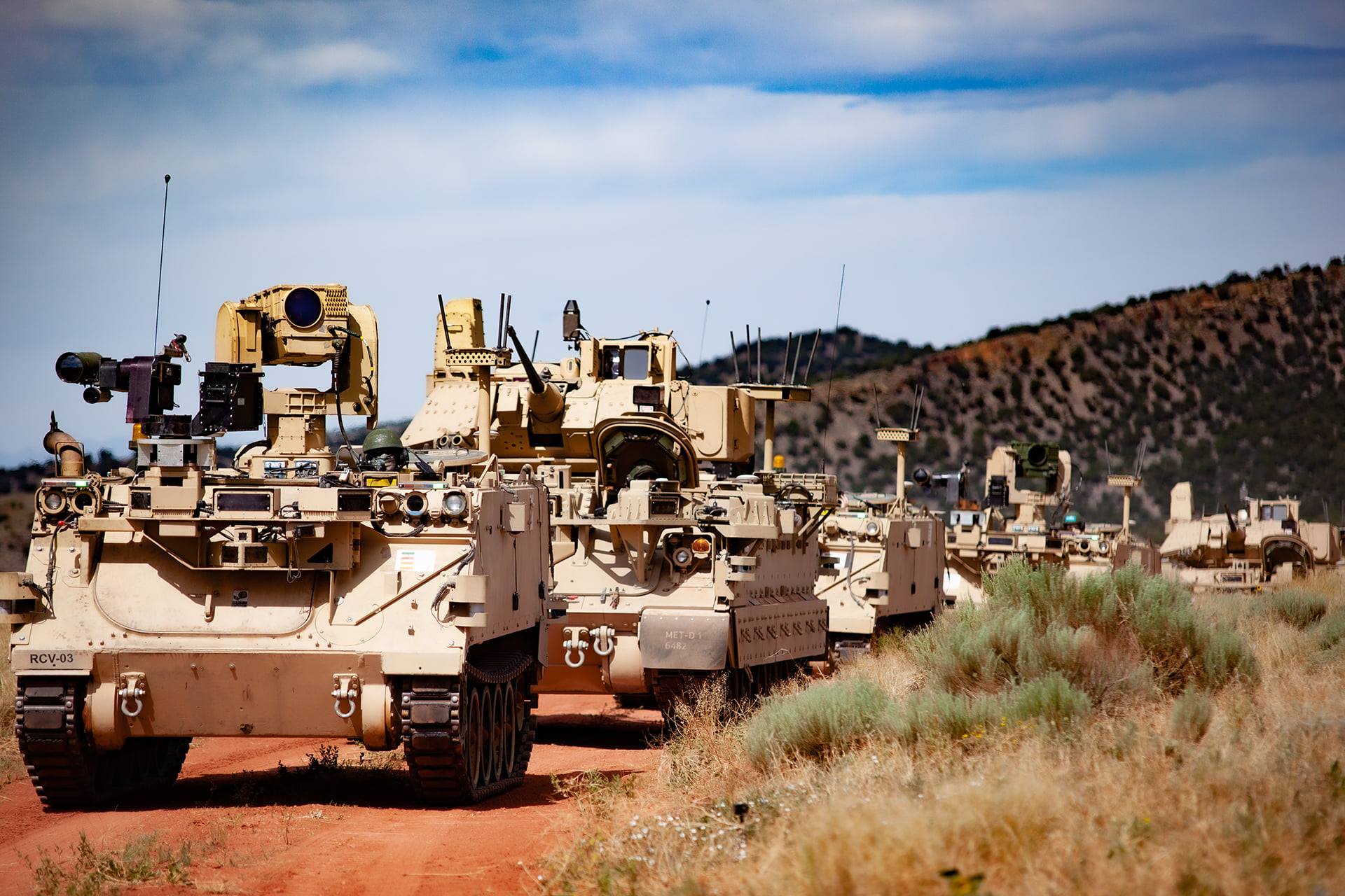 Image of military vehicles driving on dirt roads.