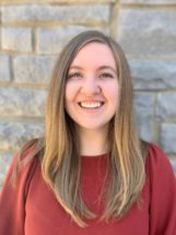 NSF Fellowship recipient in front of a brick wall smiling, woman