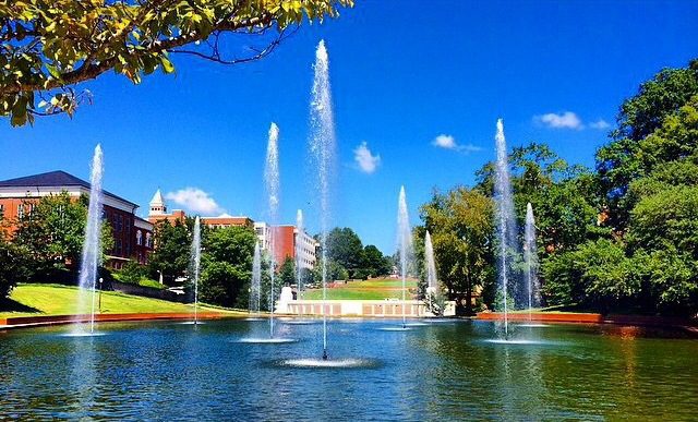 A wide campus view of the library with fountains in the reflection pool spraying in the foreground.