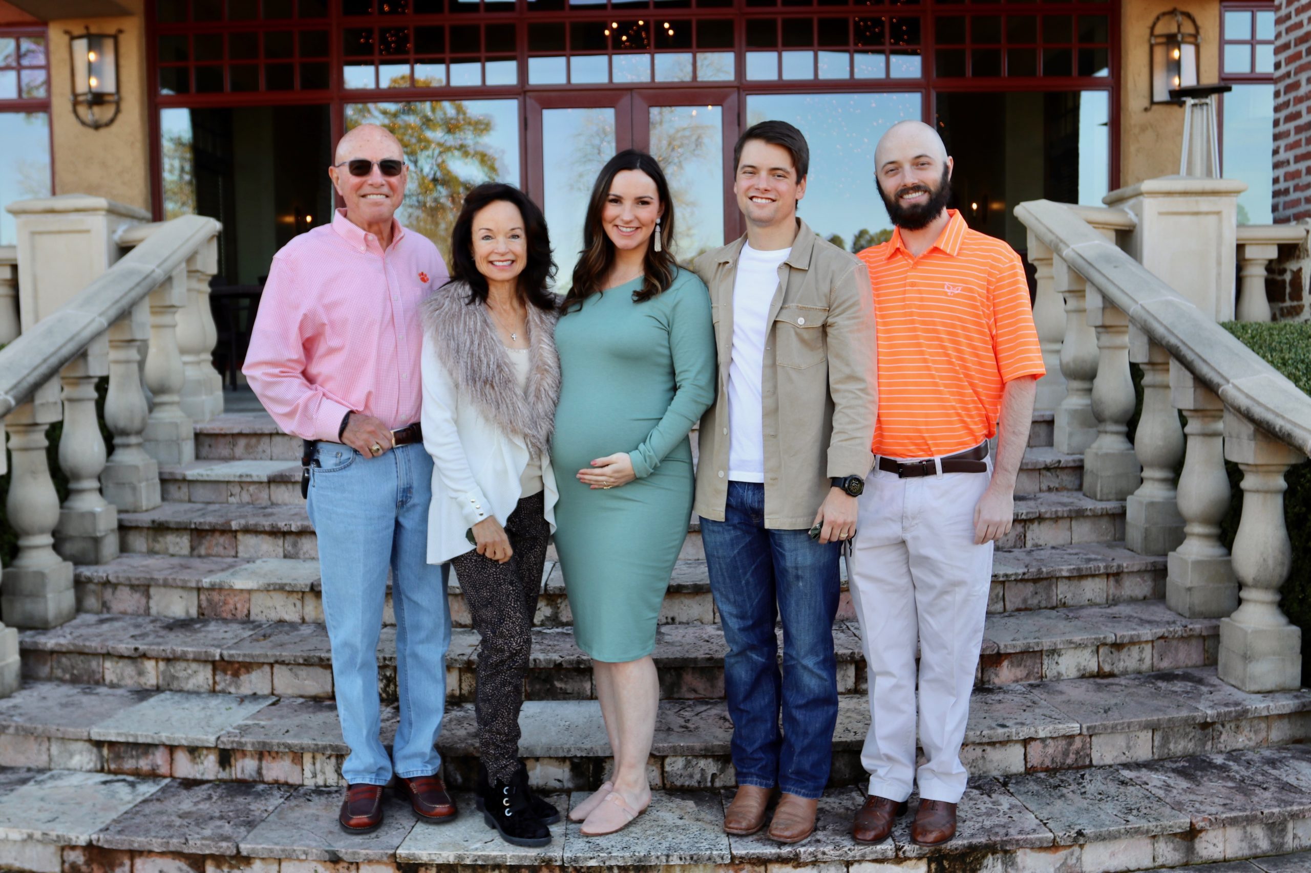 An outdoor portrait of the Glenn family standing on steps outside a home.