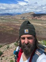 Selfie of David L. Barbeau standing at the top of a hill.