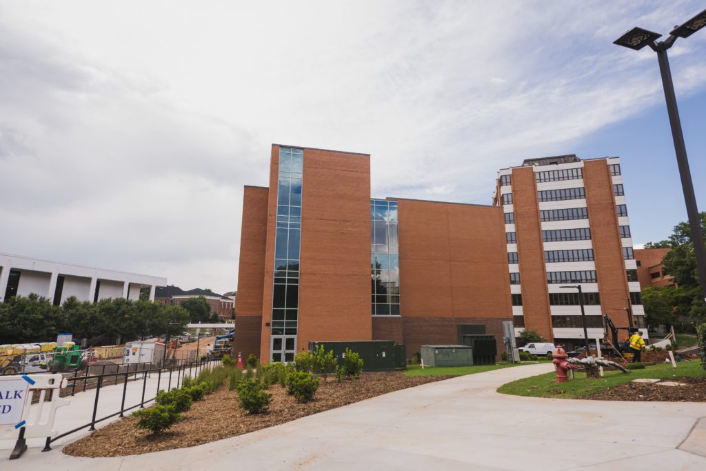 A brick building sits next to a tower building made of brick and glass.