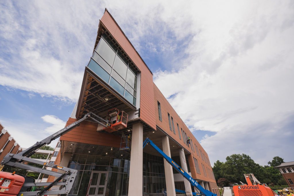 Two construction vehicles sit under a brick building.