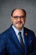John Parrish, a man with glasses wearing a blue blazer and a tie with a Tiger paw lapel pin