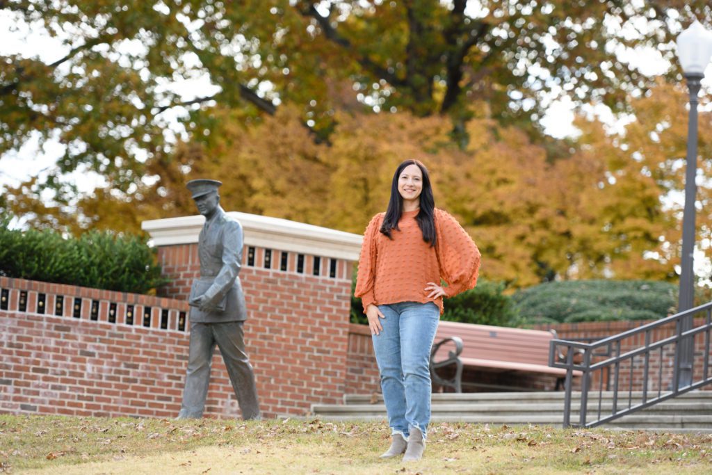 Rachelle Hales, Student Veterans Association president, stands in Clemson's military. park wearing an orange sweater.