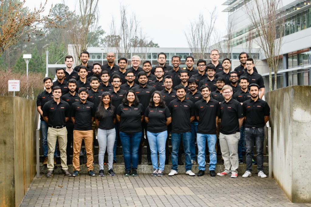 A group shot of the Deep Orange 11 team outside. All team members are wearing black polo shirts.