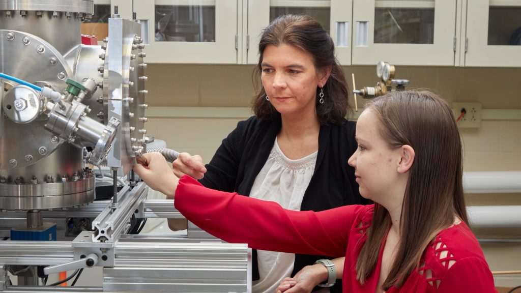 Two women work at a shiny machine