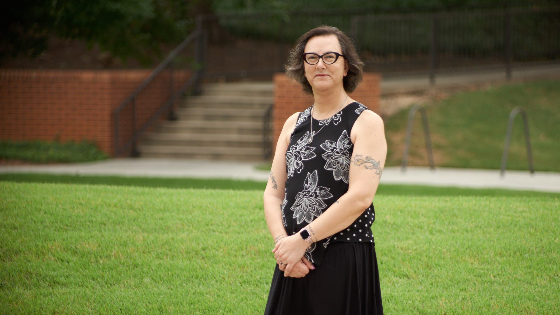 Keri Ann Sather-Wagstaff, a woman in a black outfit, stands in front of Long Hall.