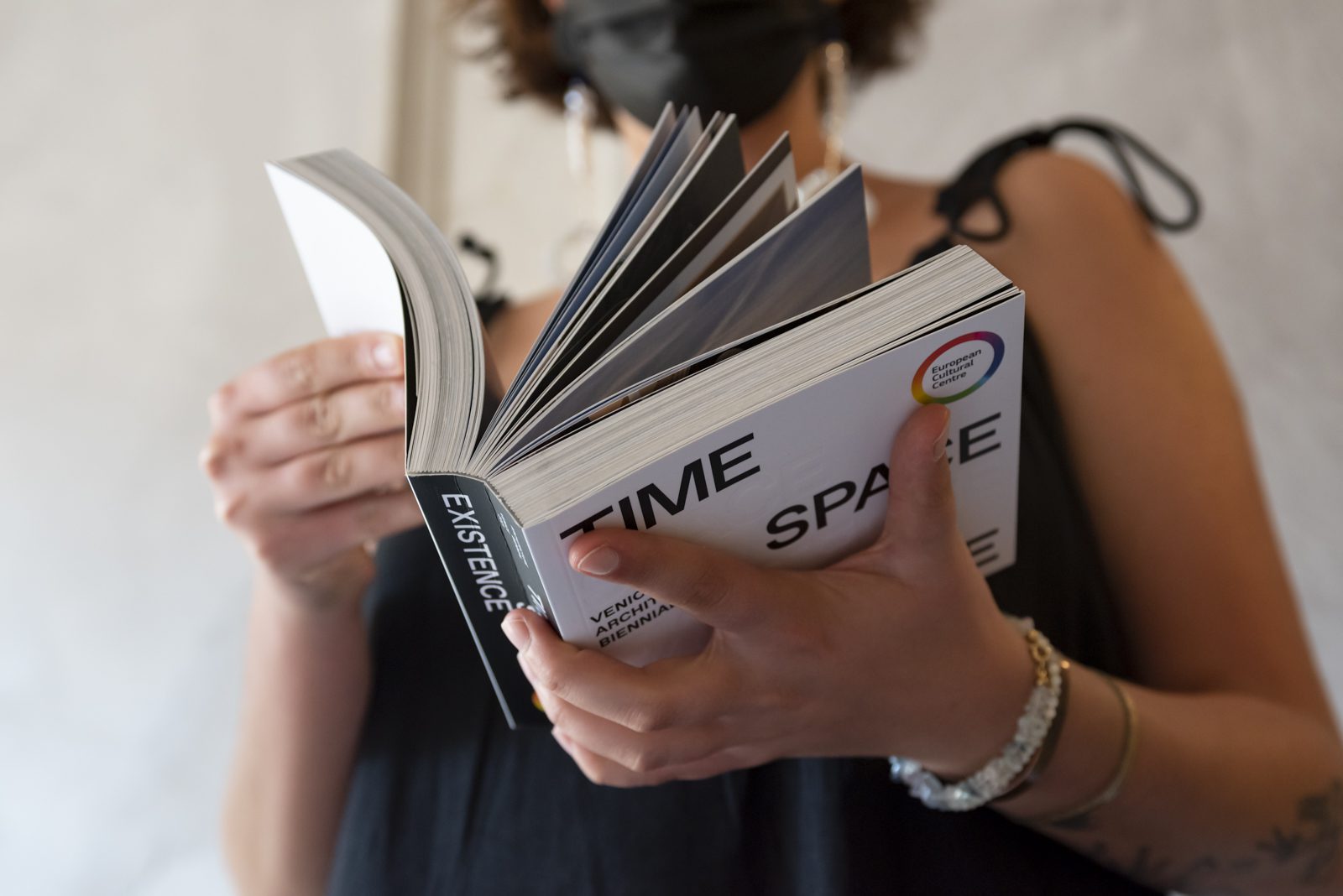 A woman looking through the published catalog of work from Time Space Existence 2021.