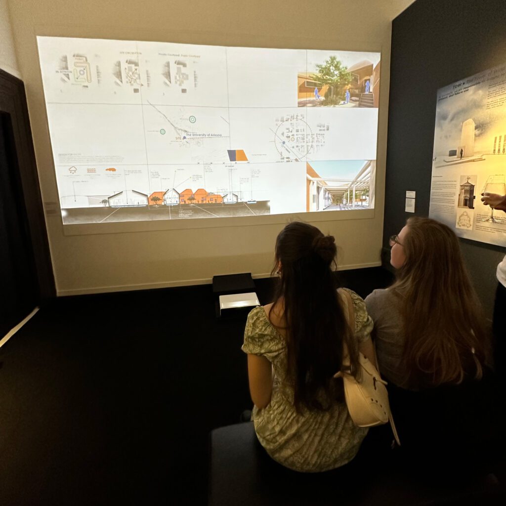 Two women sitting on a bench watching the School of Architecture installation projections