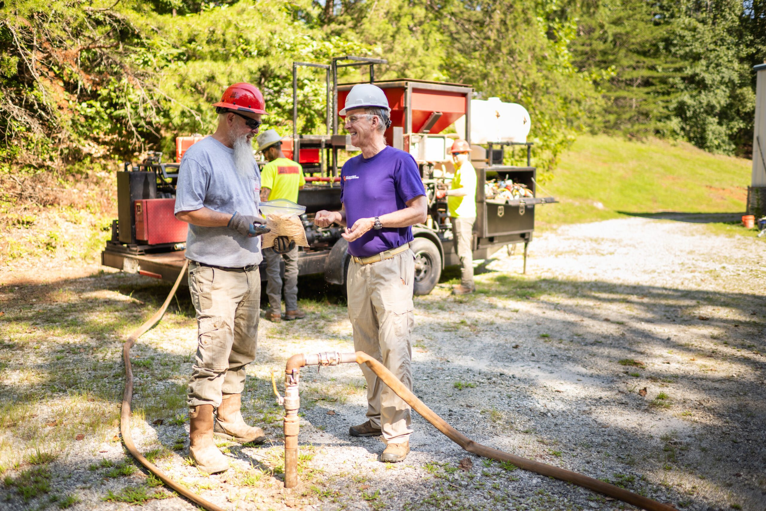 Two men stand outside in hardhats.