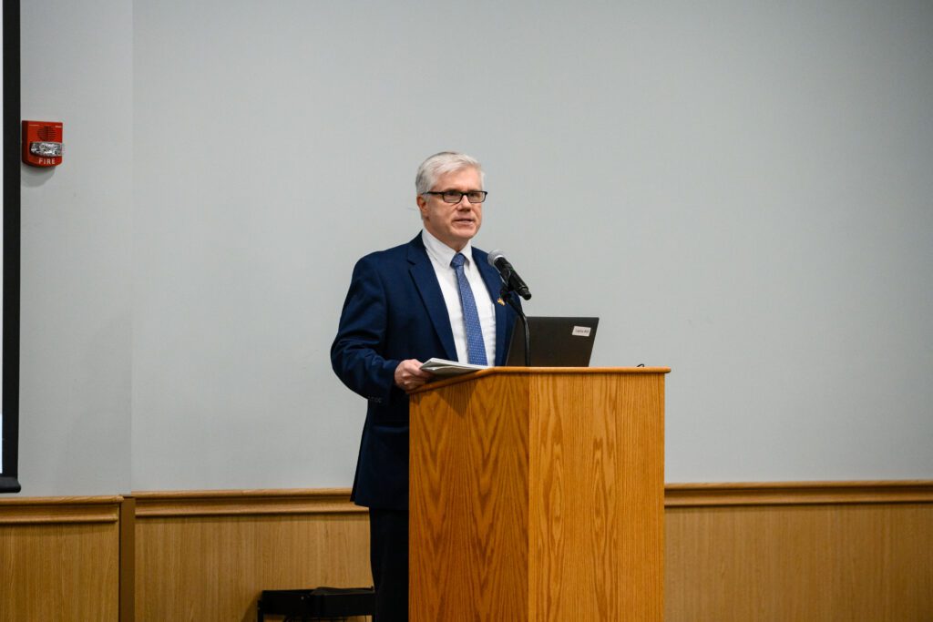 Lee Ferrell speaks from a podium inside the Hendrix Student Center.