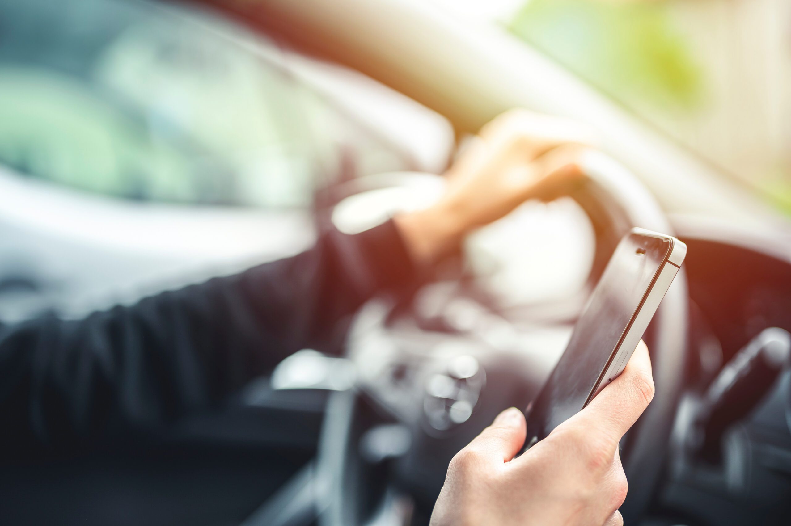 Woman looking at mobile phone while driving a car.