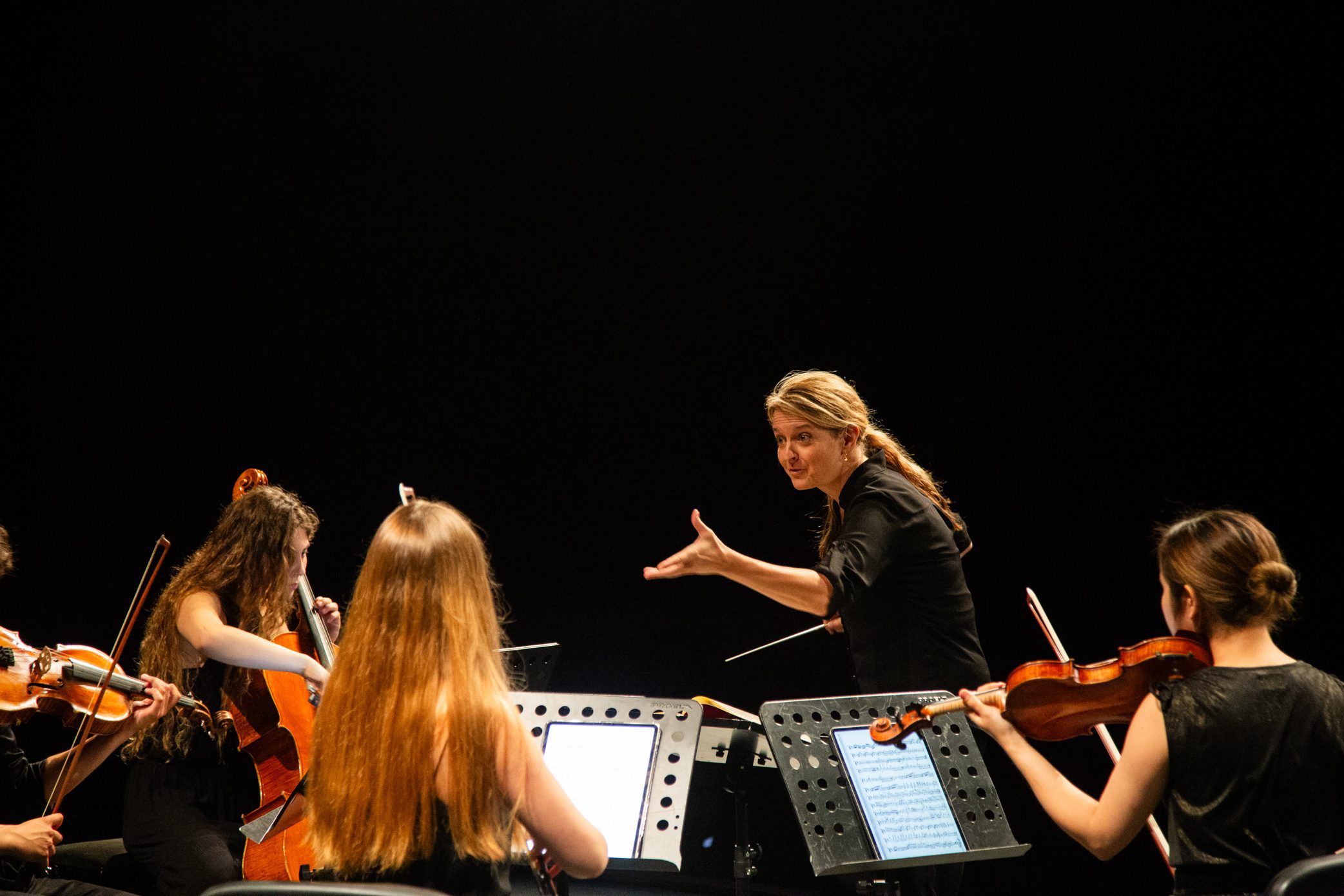 A composer intensely orchestrates a group of musicians.