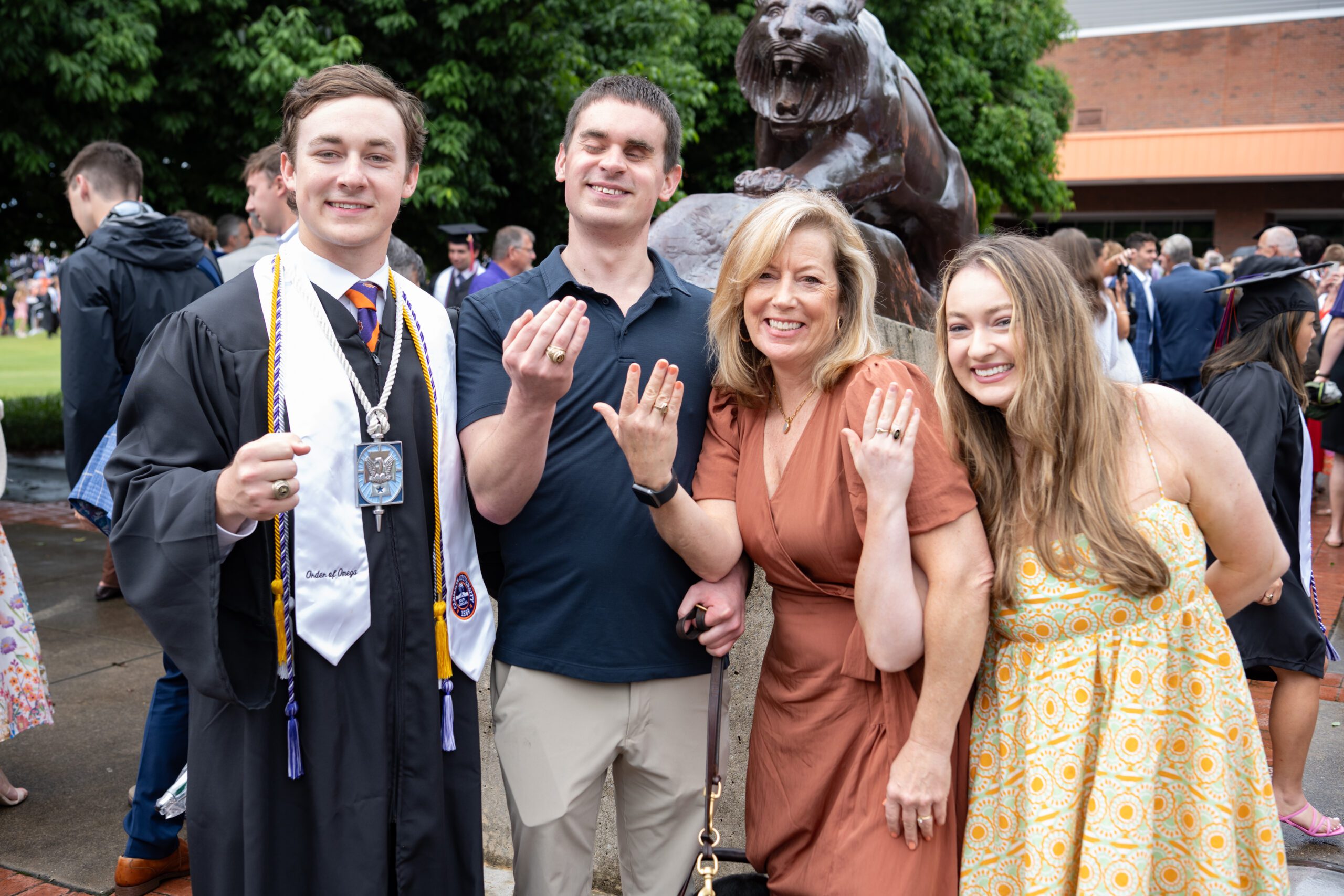 A family of four smile and flash their Clemson rings