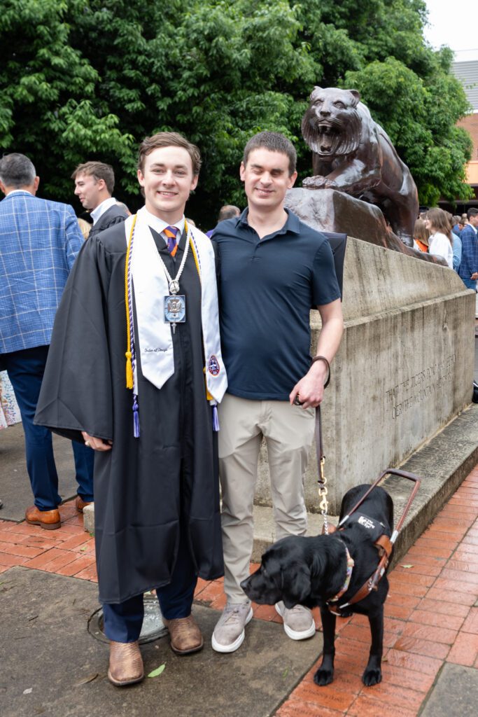 Jared ’24 and Ryan Uhle ’19 pose for a picture outside of Clemson's Littlejohn Coliseum after graduation ceremonies in May 2024 with Ellana.