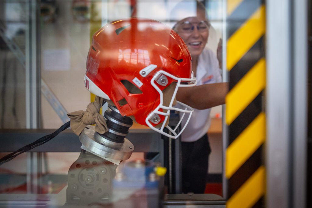 A Clemson orange football helmet undergoes a test inside a glass case in the CHIP lab.