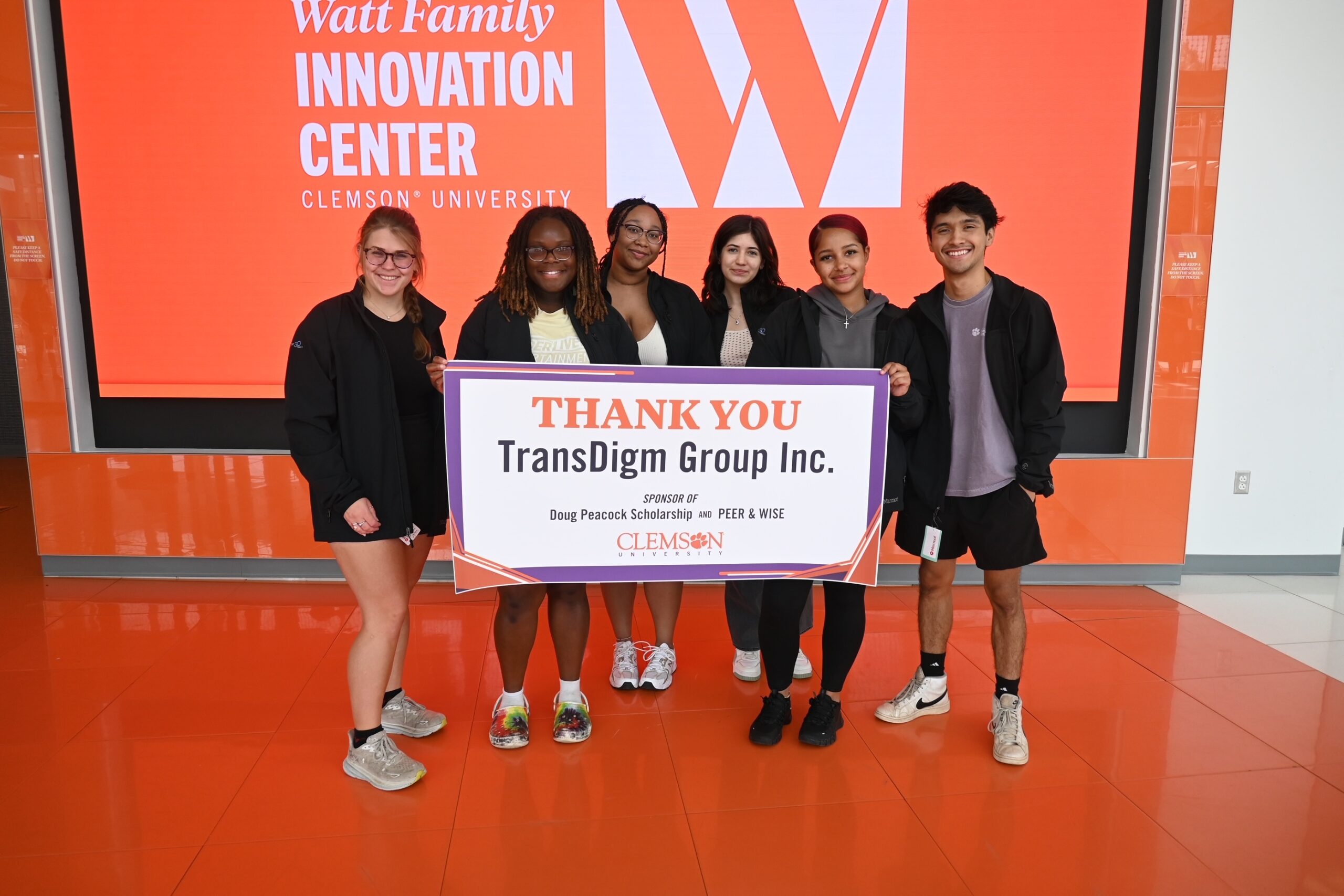 Six Clemson students holding a banner that says "Thank you TransDigm Group Inc. Sponsor of Doug Peacock Scholarship and Peer & Wise"