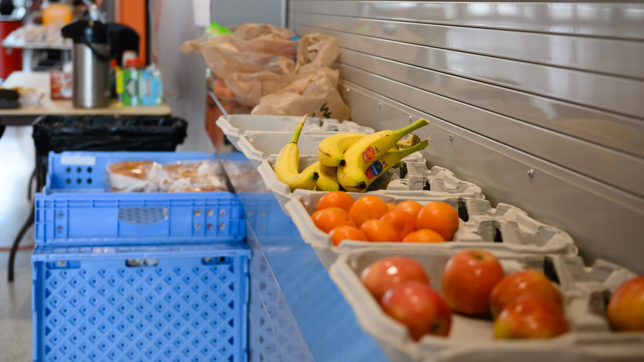 Bananas and oranges next to blue bins.