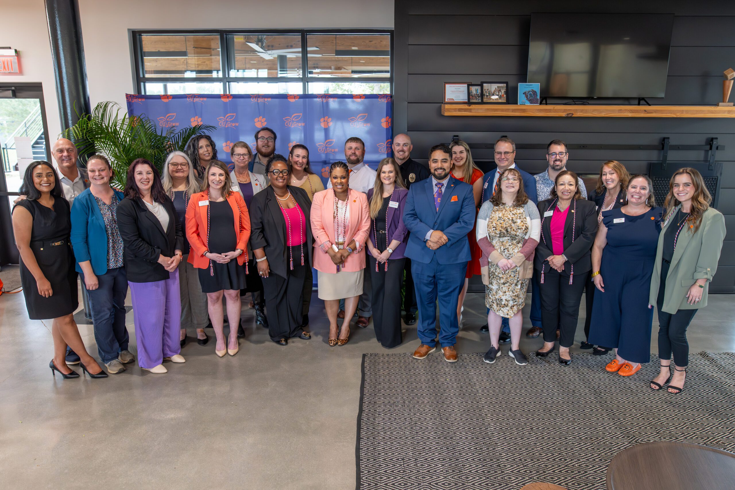 A group of individuals pose for a group photo in front of the CU Grow photo backdrop.