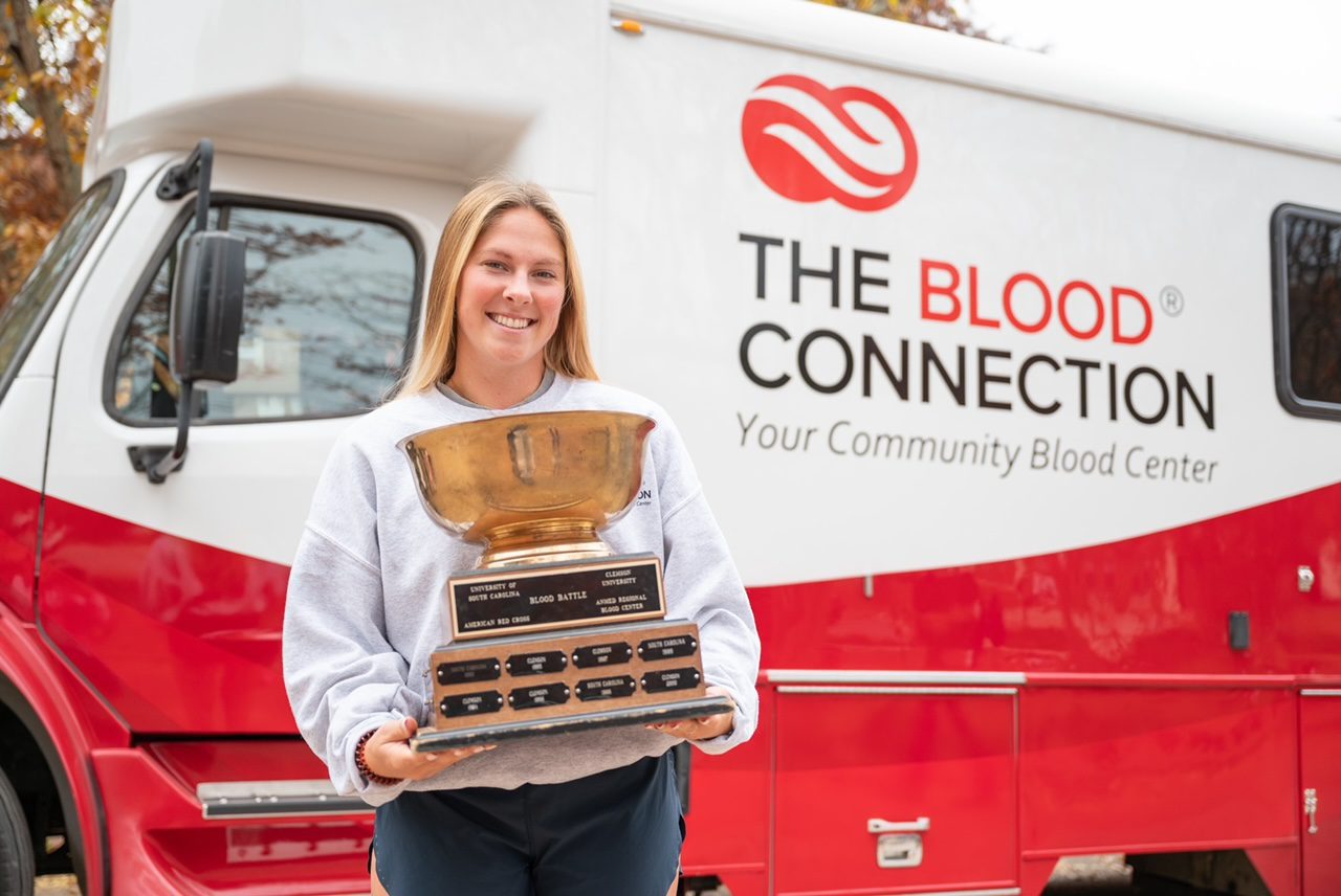 Lindsey Schmidt, co-chair of the 2024 Blood Bowl, hoists the 2023 trophy