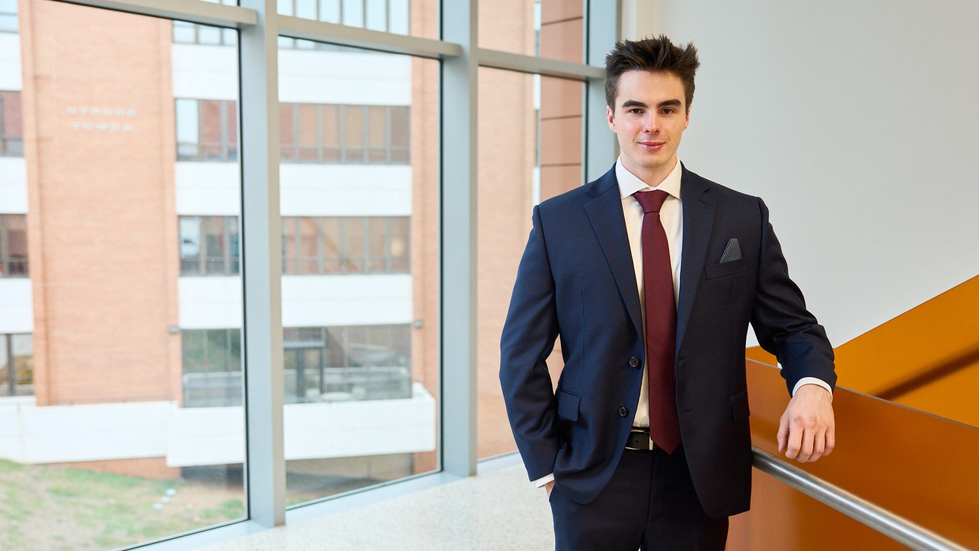 Adam Gatch, Clemson's third Churchill Scholar, leaning against a staircase.
