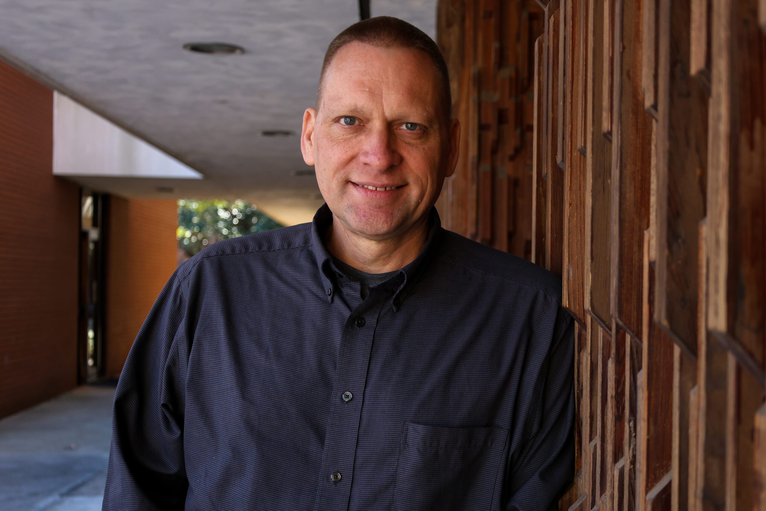 Wayne Phillips leaning on a wall and smiling