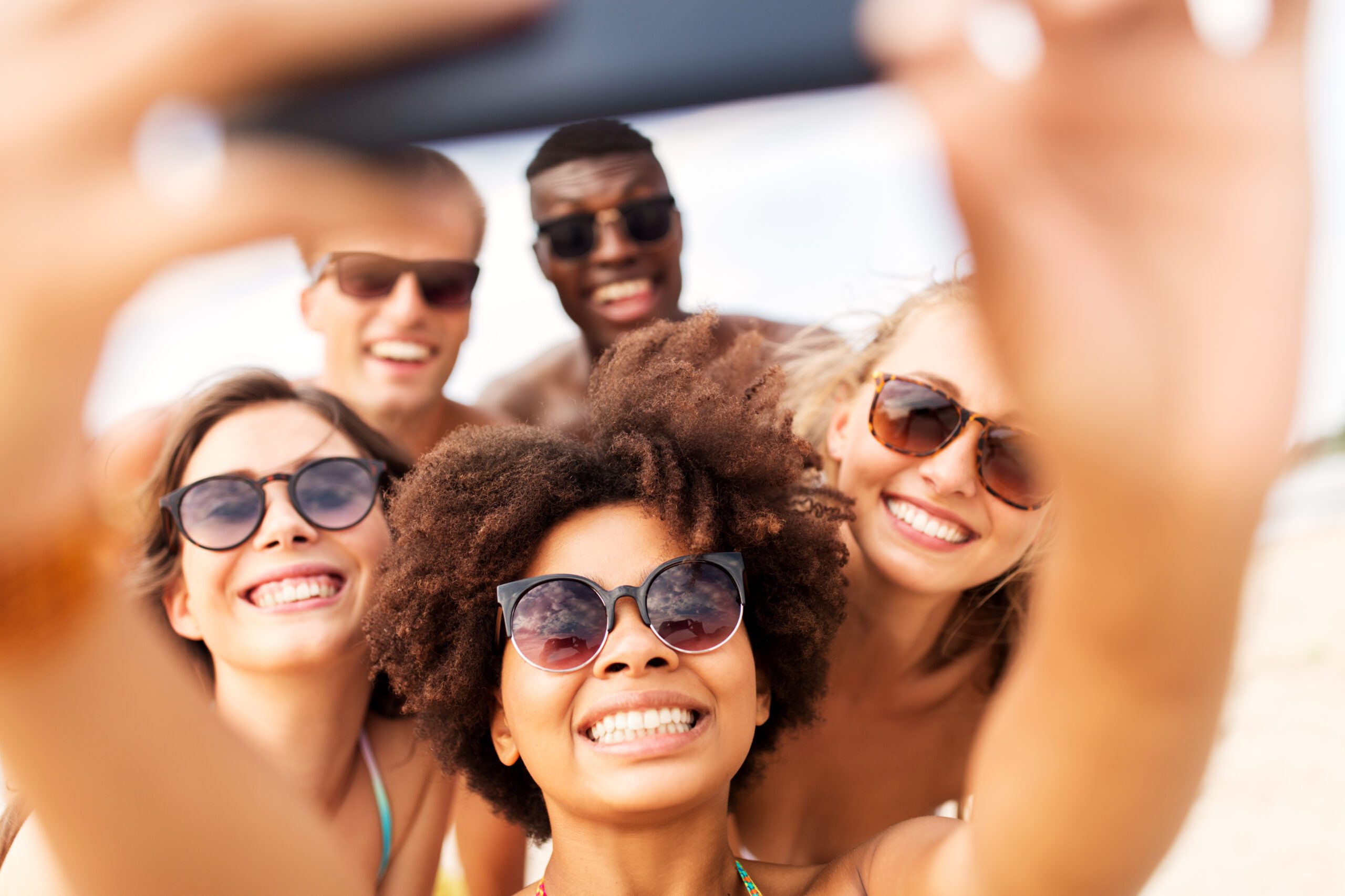 group of happy friends taking picture by smartphone on beach
