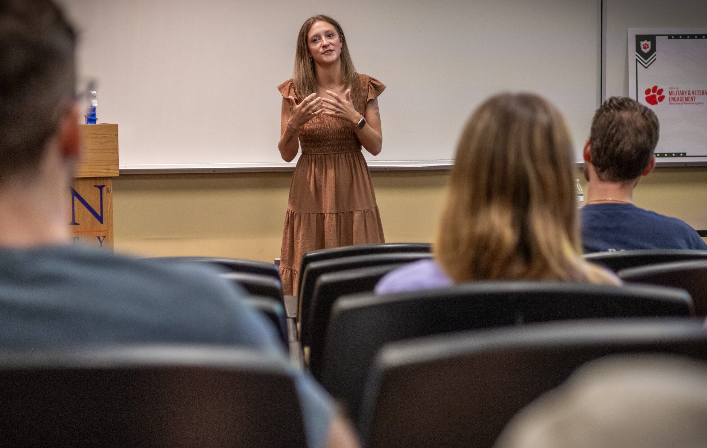 a young woman talks in front of a group of people