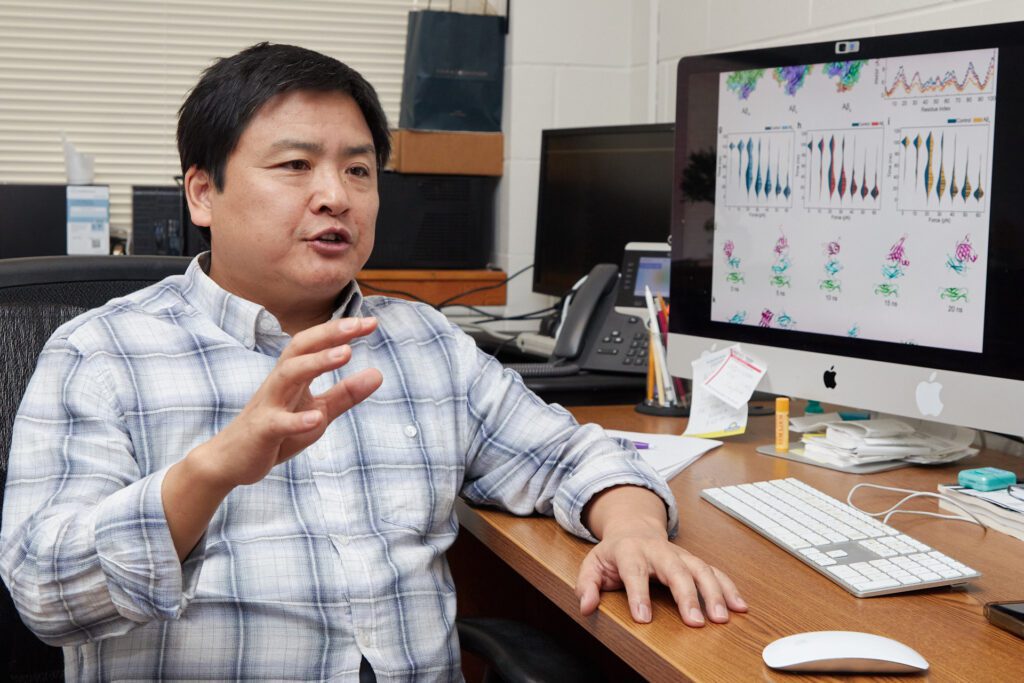 Man sitting at desk in front of computer gestures.