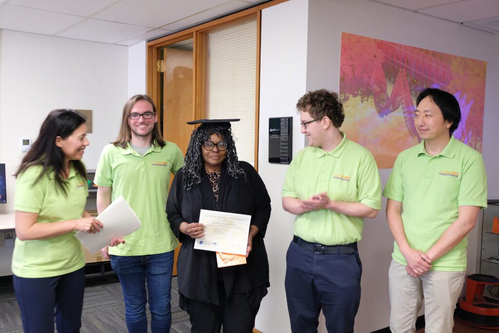 Darlene Talbert smiles as she is surrounded by GIS team members at graduation