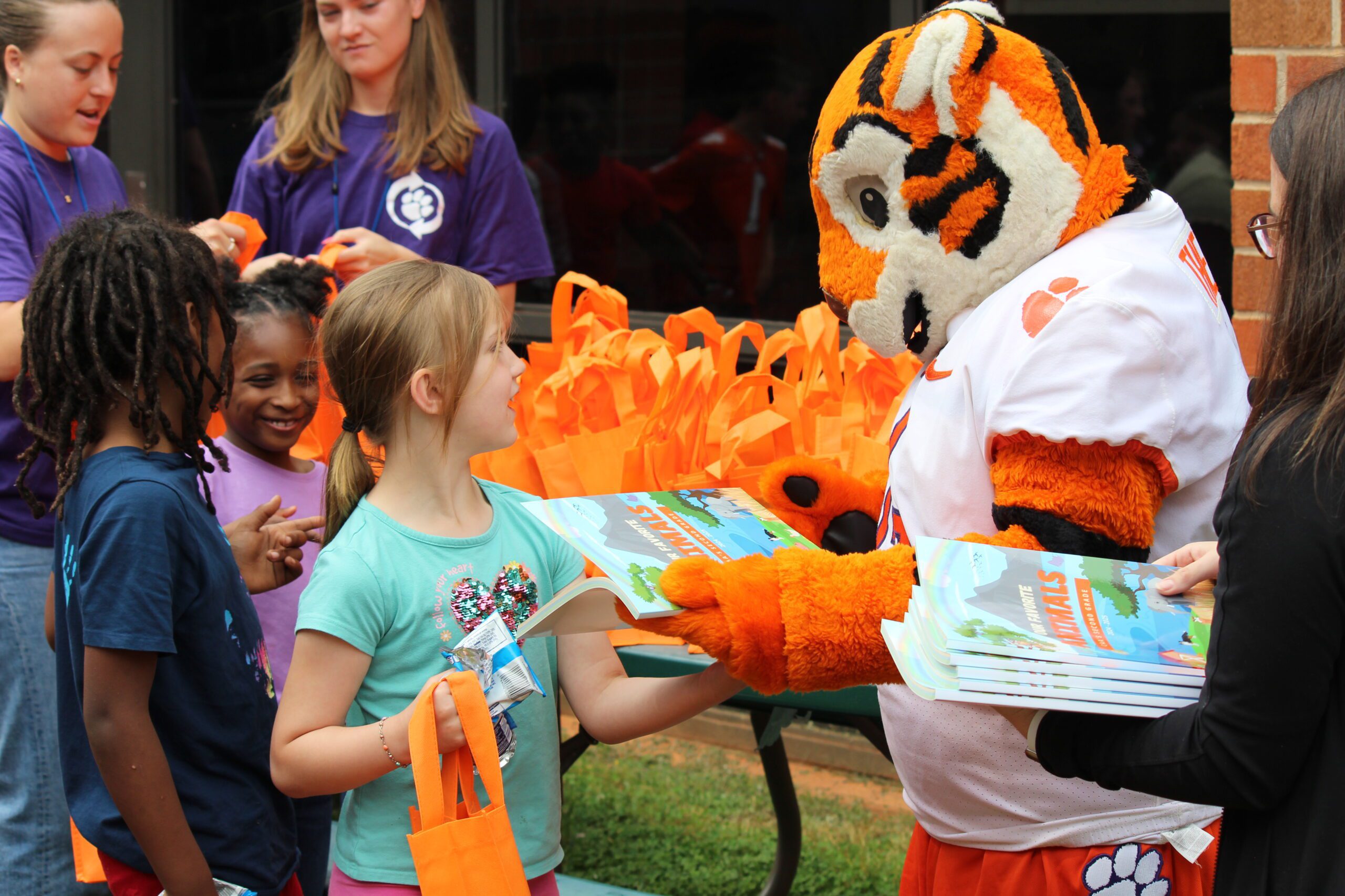 Tiger Cub hands elementary student their book
