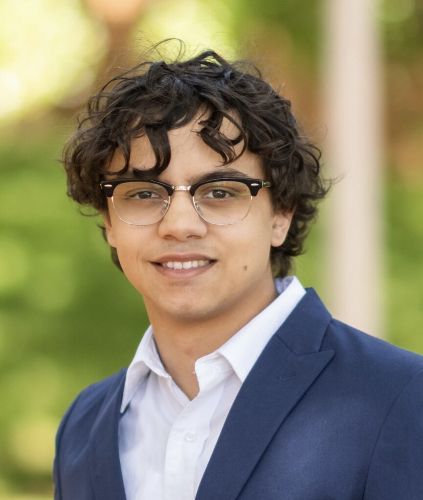 Thomas Ross in a white shirt, jacket and wearing glasses.