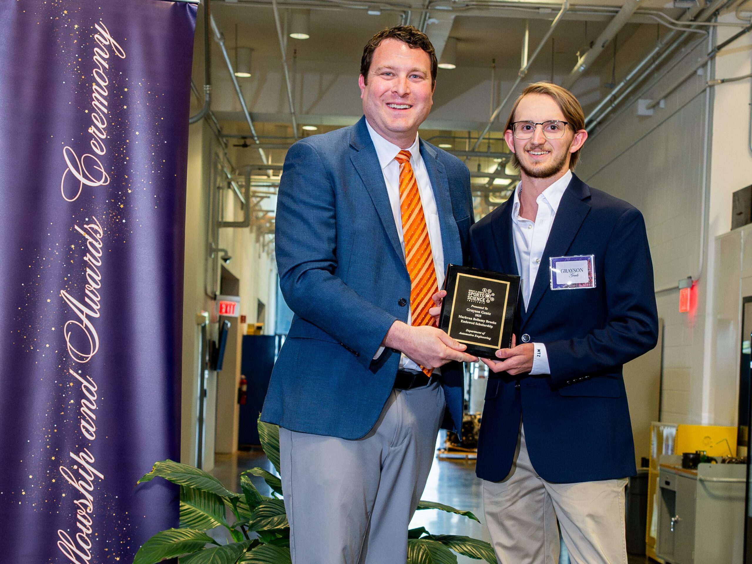 Two men posing with an award