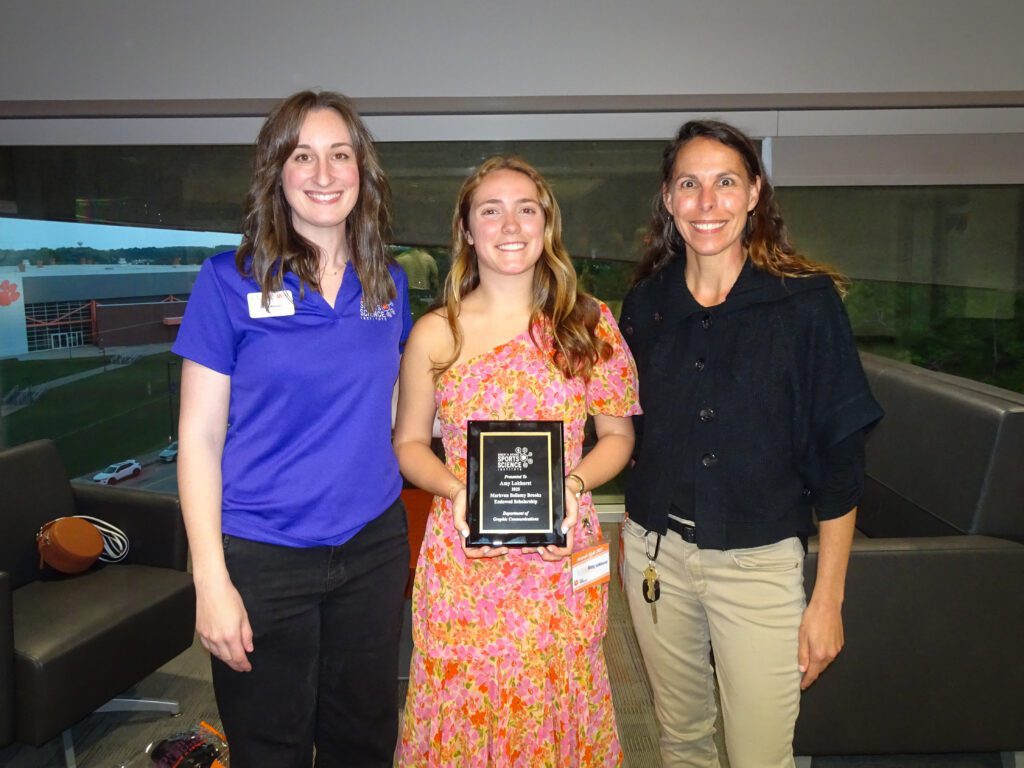 Three women posing with an award