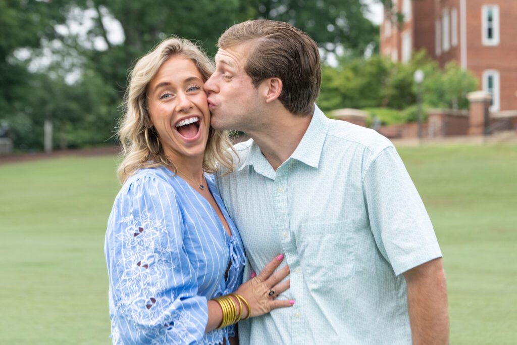 A young man kisses his sister on the cheek, making her laugh