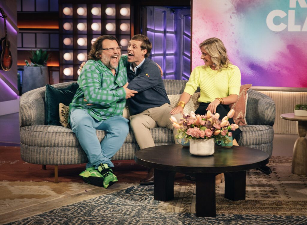 Tanner Smith sits on a couch and gives actor Jack Black a hug while his sister, Midge, looks on