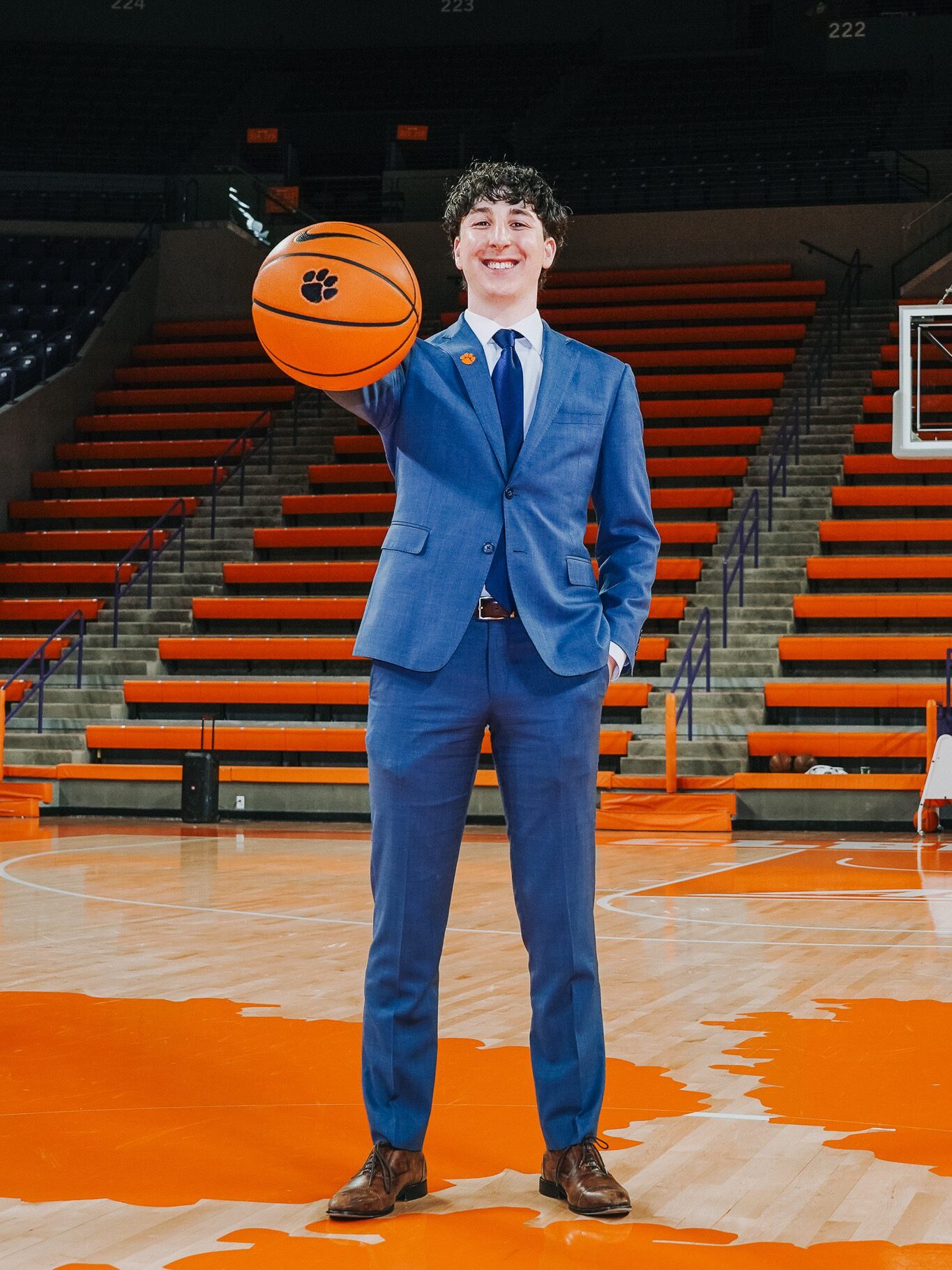 A man holding a Clemson basketball on the court, he is a Brooks scholar