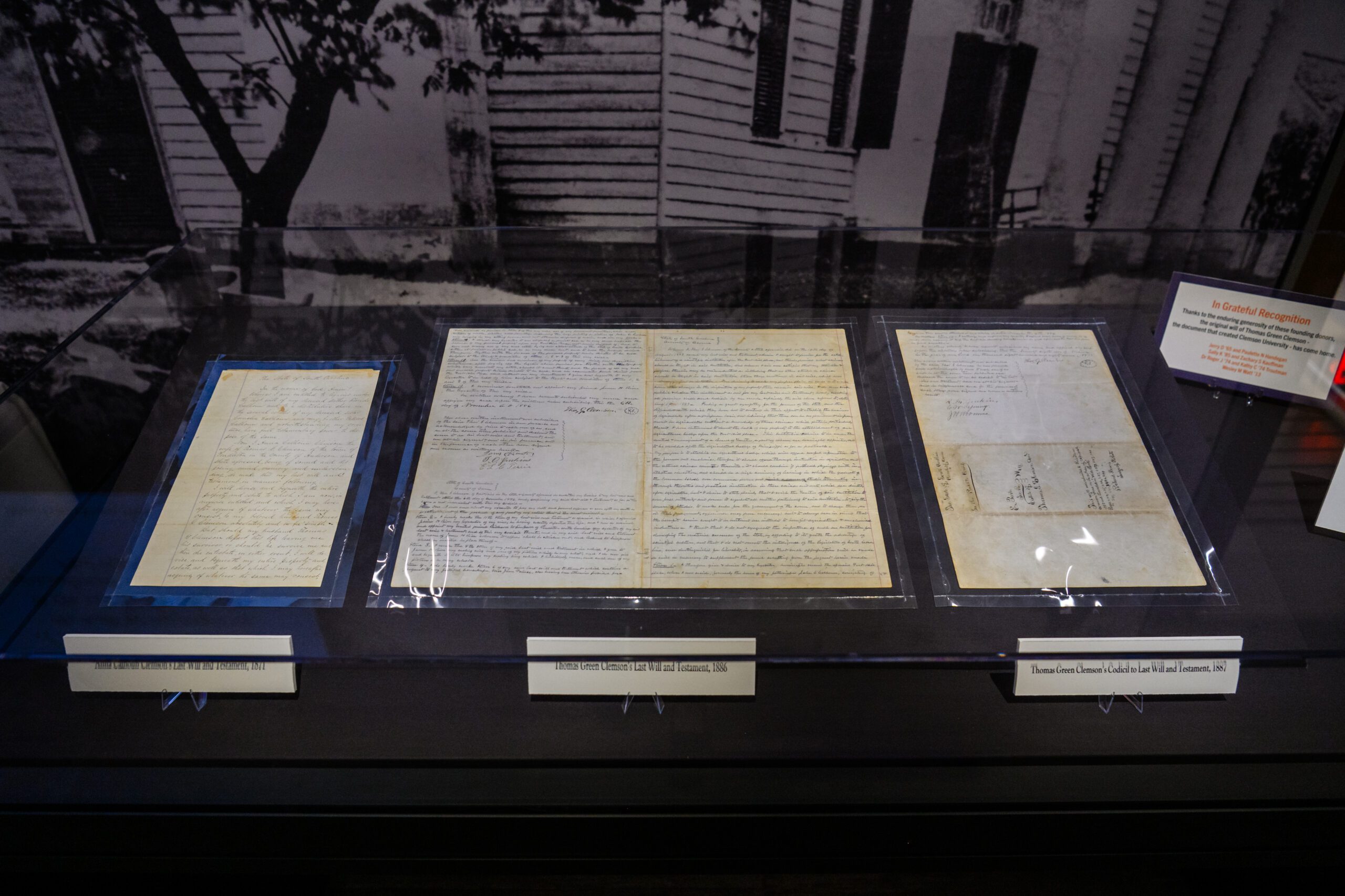 Three aged documents covered by glass lay on a table.