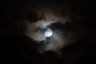 A waxing gibbous moon with some clouds.