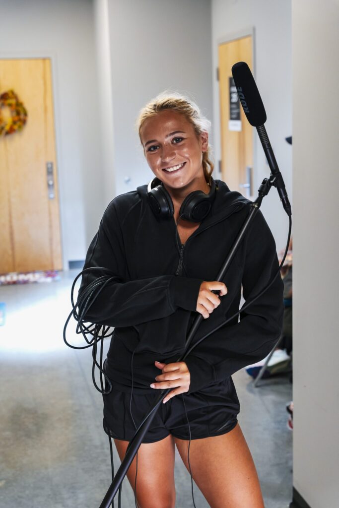 World Cinema student Hannah Noe holds a boom microphone and smiles