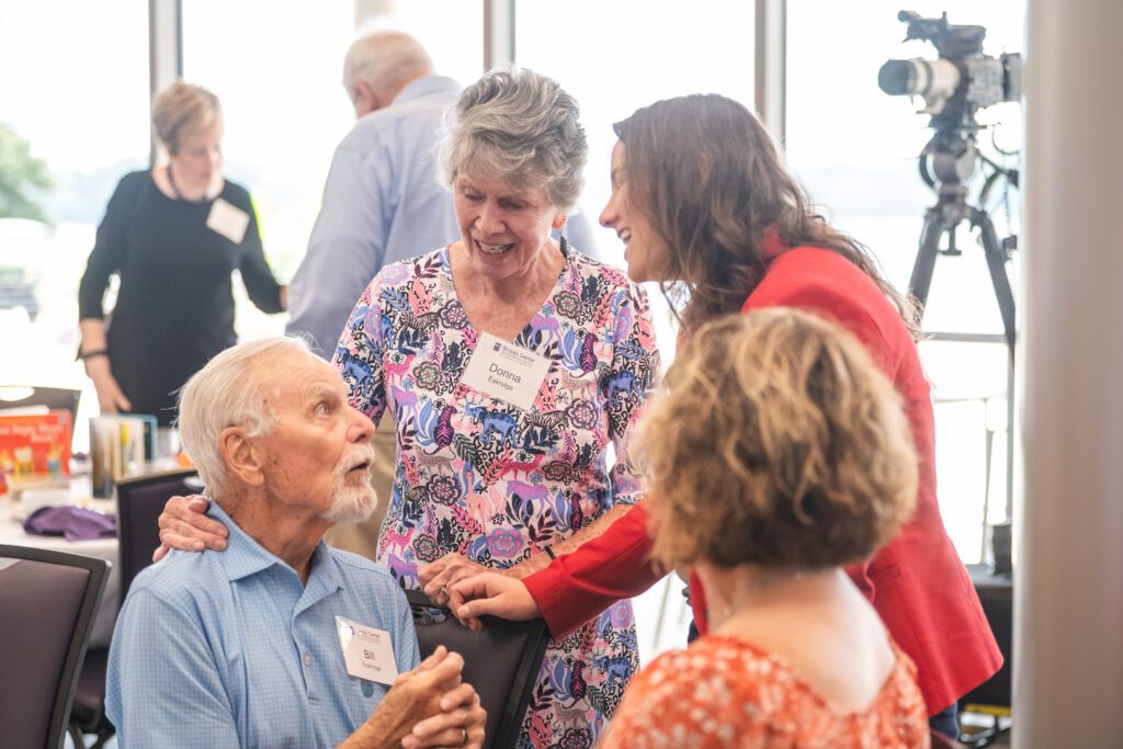 a group of people stand around a table talking and smiling