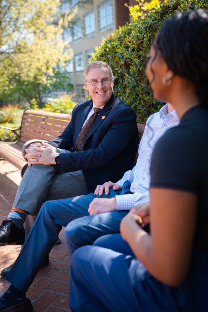 Doug Hallenbeck speaks with students on a campus bench