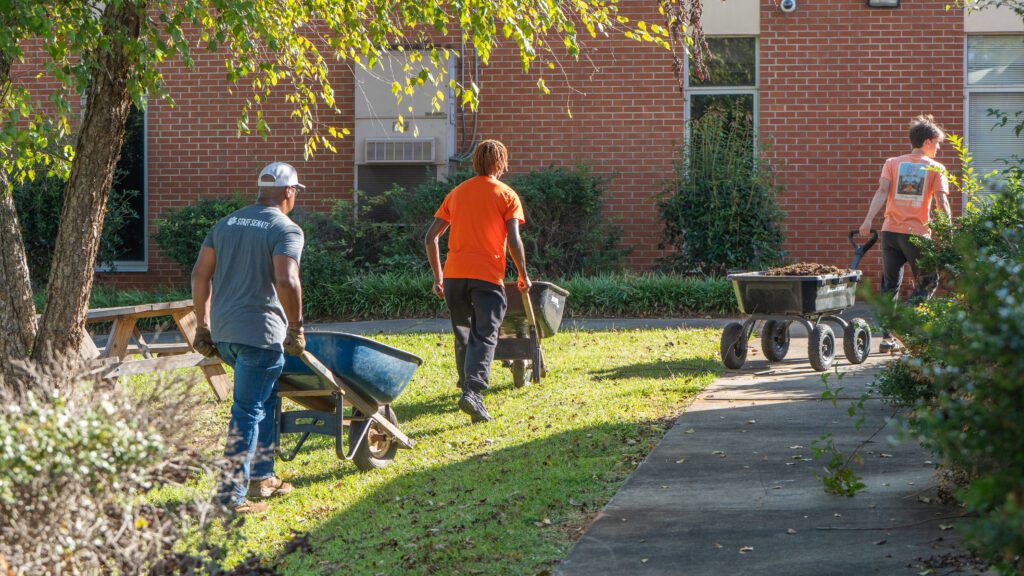 Student and staff volunteers haul loads of mulch.