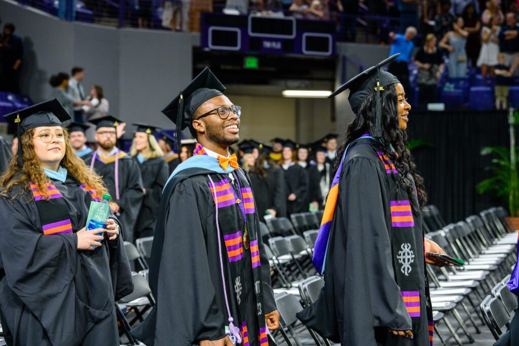A graduate smiles during the processional for Commencement in Littlejohn Coliseum