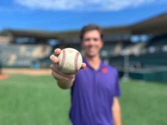 Bioengineering Ph.D. student Connor Moore holds a baseball in Doug Kingsmore Stadium