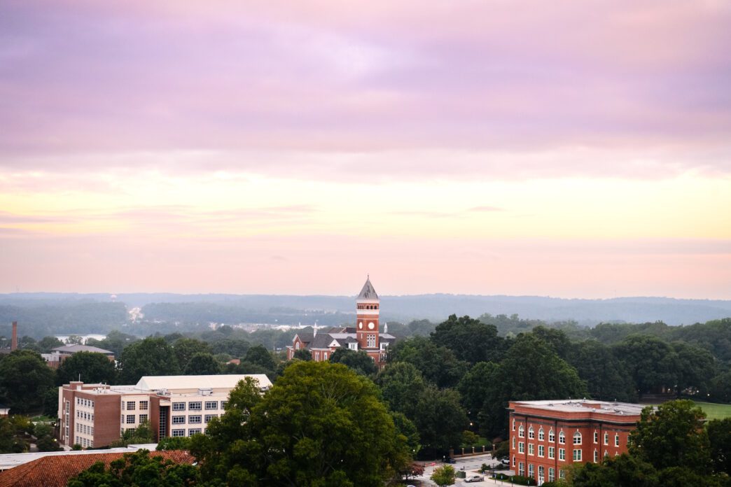 Sunrise over Clemson University, aerial view of Old Main/Tillman Hall peaking out from amongst tall trees