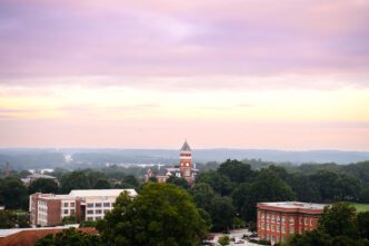 Sunrise over Clemson University, aerial view of Old Main/Tillman Hall peaking out from amongst tall trees