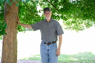 Provost Bob Jones stands on campus against a tree