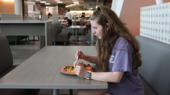 A student eats in a dining hall.